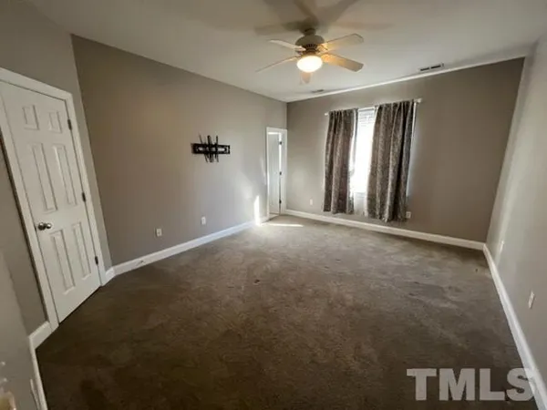 an empty room with windows and fan