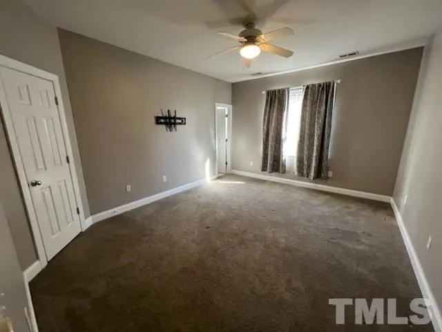 an empty room with windows and fan