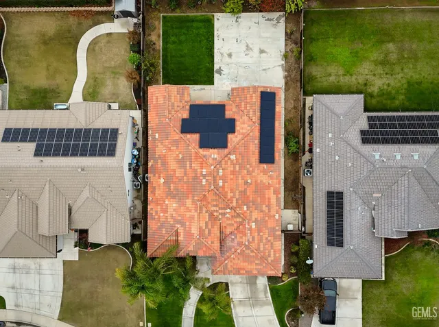an aerial view of a house with swimming pool and large trees