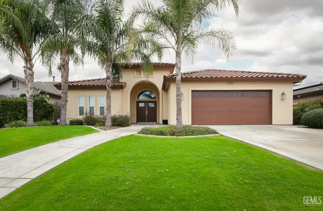 a front view of a house with a garden and palm trees