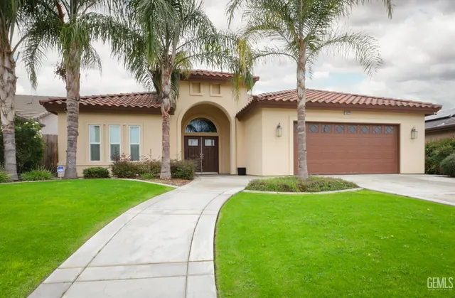 a front view of a house with a garden and palm trees