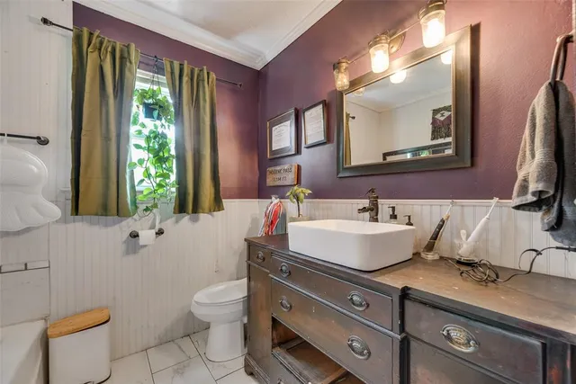 a bathroom with a granite countertop sink a toilet a mirror and a window