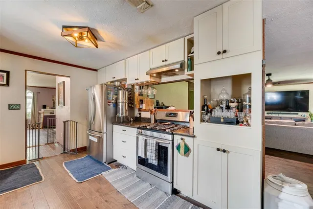 a kitchen with stainless steel appliances a stove refrigerator and cabinets