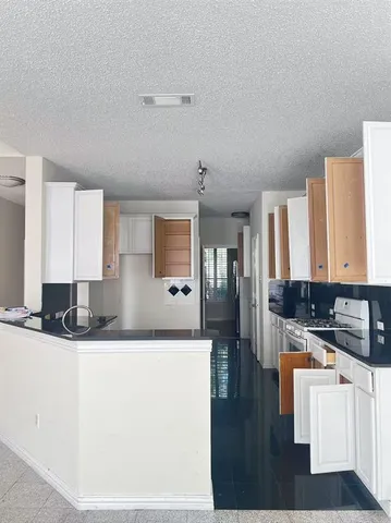 a kitchen with granite countertop a sink and a stove top oven