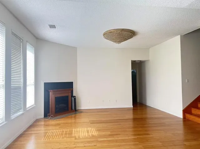 a view of an empty room with window and wooden floor