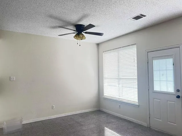 an empty room with a window and a fan