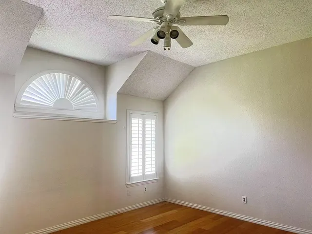 an empty room with a window and a chandelier fan
