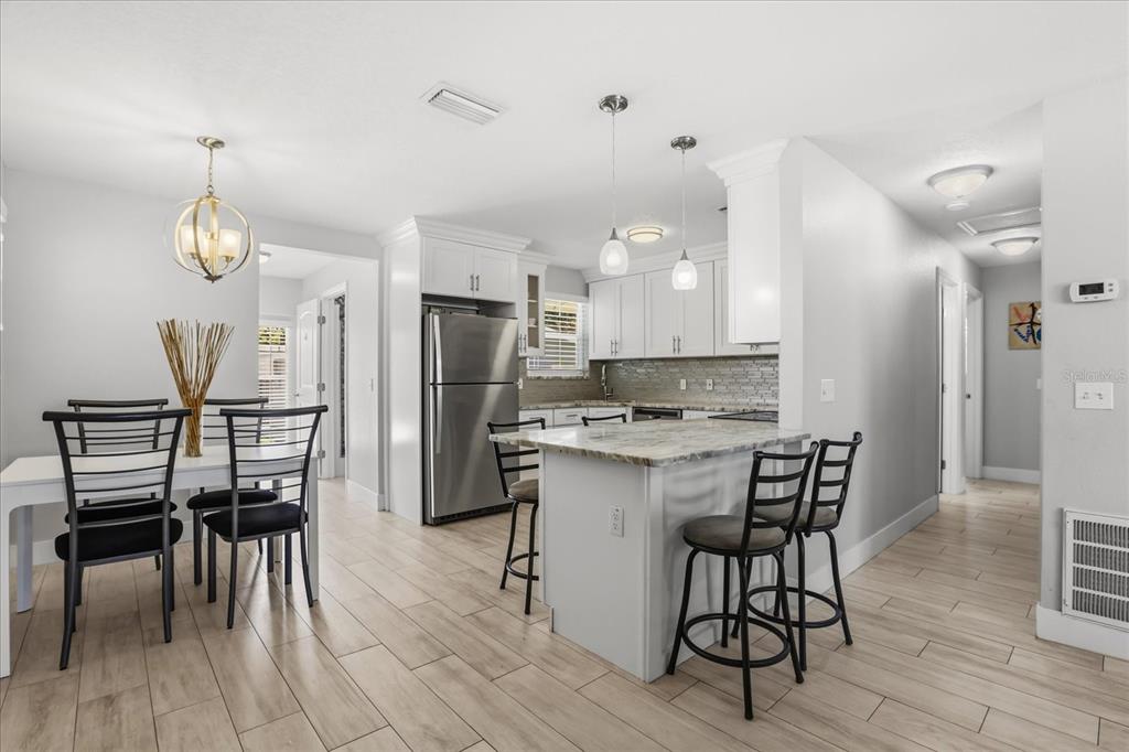 159 Holland Road Ormond Beach, FL 32176 - Photo 7 of 55 a kitchen with stainless steel appliances kitchen island granite countertop a table chairs and a refrigerator