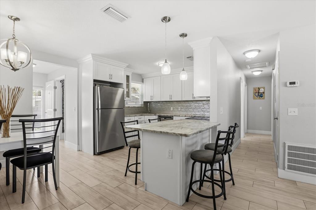 159 Holland Road Ormond Beach, FL 32176 - Photo 8 of 55 a kitchen with stainless steel appliances a dining table chairs stove refrigerator and cabinets