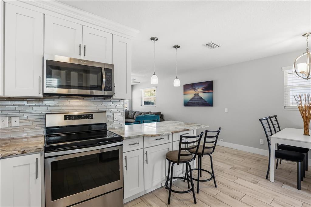 159 Holland Road Ormond Beach, FL 32176 - Photo 10 of 55 a kitchen with granite countertop a stove a microwave a dining table and chairs