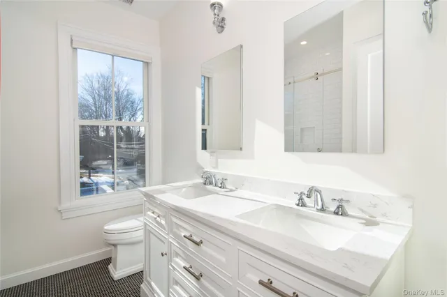 a bathroom with a granite countertop sink a toilet and a large mirror