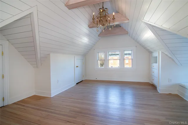 an empty room with wooden floor chandelier and windows