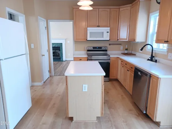 a kitchen with kitchen island a sink a stove a refrigerator and wooden cabinets