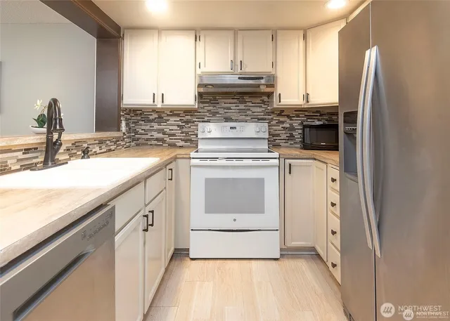 a kitchen with stainless steel appliances granite countertop a stove a sink and a refrigerator