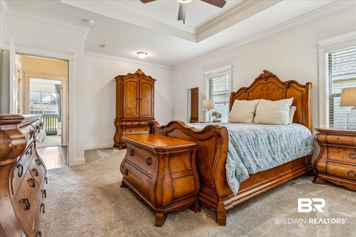 7088 Rocky Rd Loop Gulf Shores, AL 36542 - Photo 29 of 39 Bedroom with light carpet, multiple windows, a raised ceiling, and crown molding