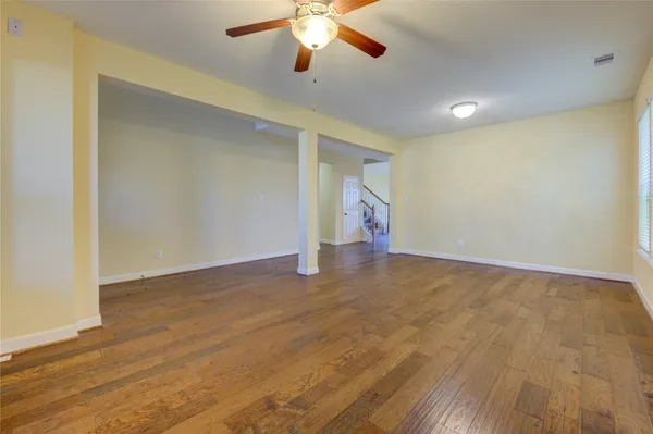 a view of an empty room with wooden floor and a window