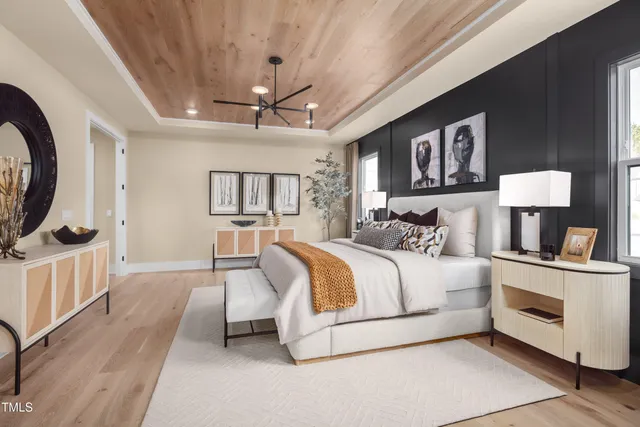 a spacious bedroom with a bed a mirror on dresser and a table