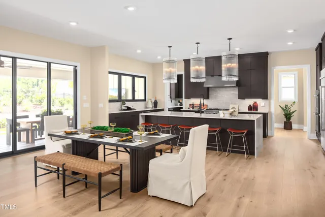 a room with stainless steel appliances kitchen island granite countertop furniture a stove a sink a dining table and chairs