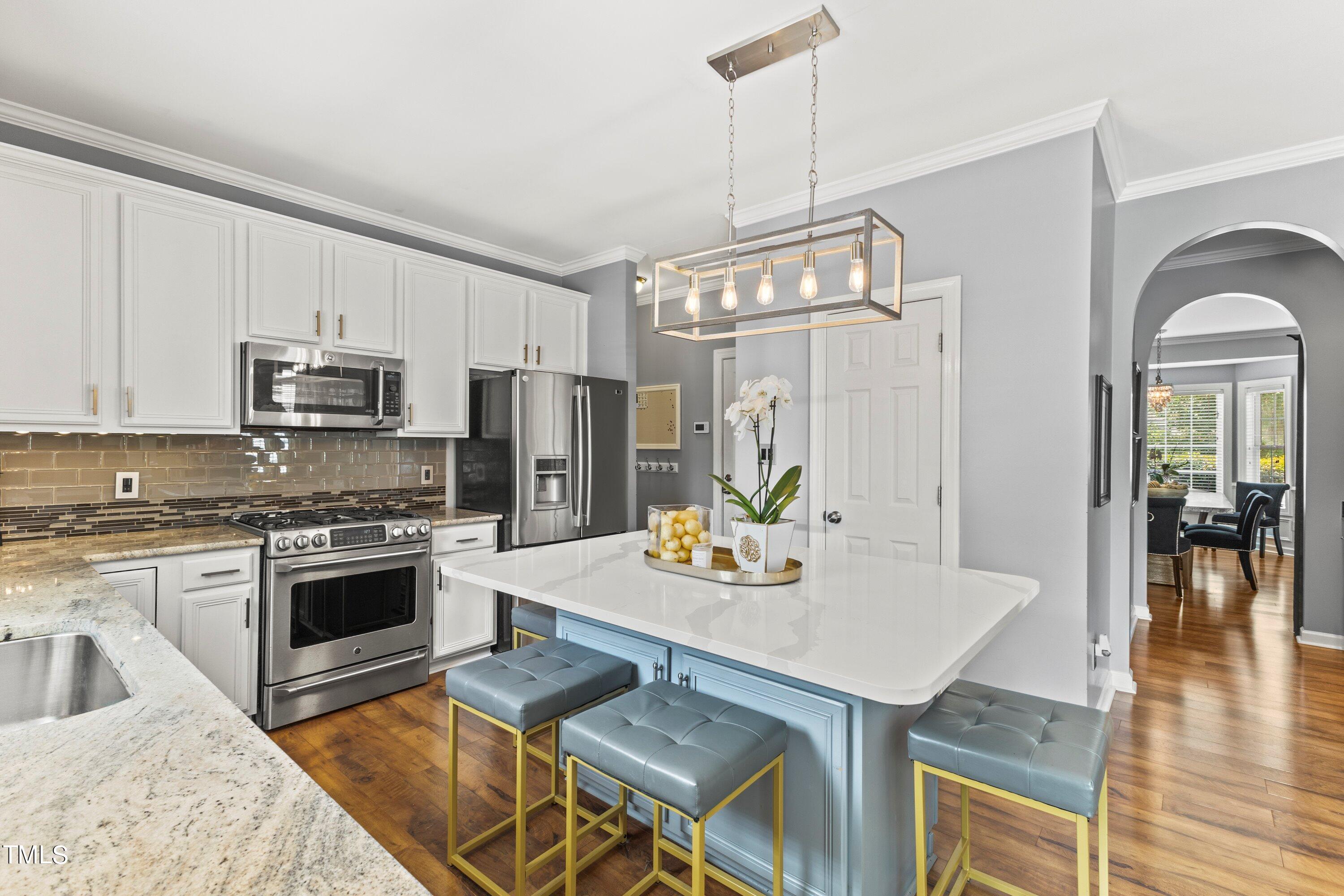 12212 Penrose Trail Raleigh, NC 27614 - Photo 16 of 41 a kitchen with stainless steel appliances granite countertop a stove a sink dishwasher a refrigerator with a dining table and chairs with wooden floor