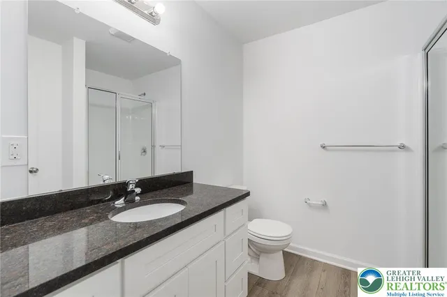 a bathroom with a granite countertop sink a toilet and a mirror