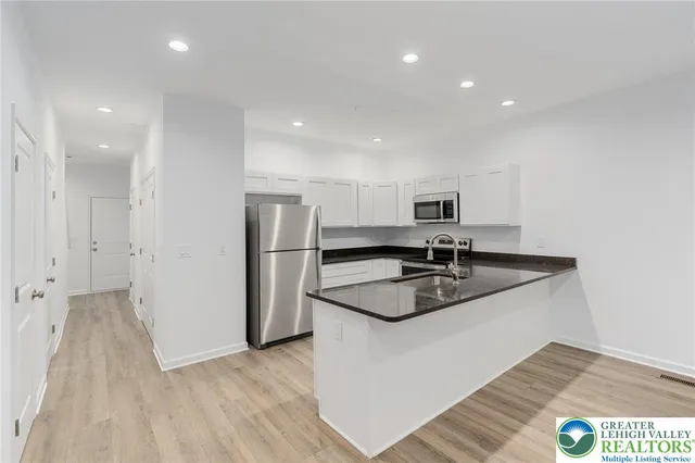 a kitchen with stainless steel appliances granite countertop a sink and a refrigerator