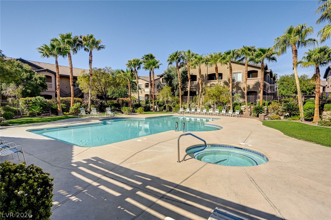 8985 South Durango Drive, Unit 2187 Las Vegas, NV 89113 - Photo 54 of 73 An inviting resort-style pool and spa await, surrounded by swaying palms and lush landscaping.