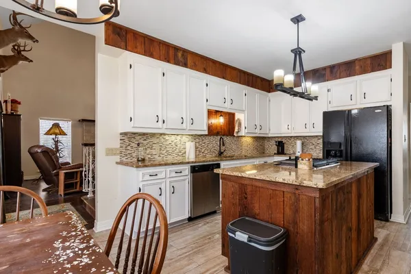 a kitchen with stainless steel appliances granite countertop a sink a stove and a wooden floors