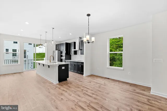 a large white kitchen with stainless steel appliances kitchen island granite countertop a refrigerator a oven a sink with a countertop and chairs