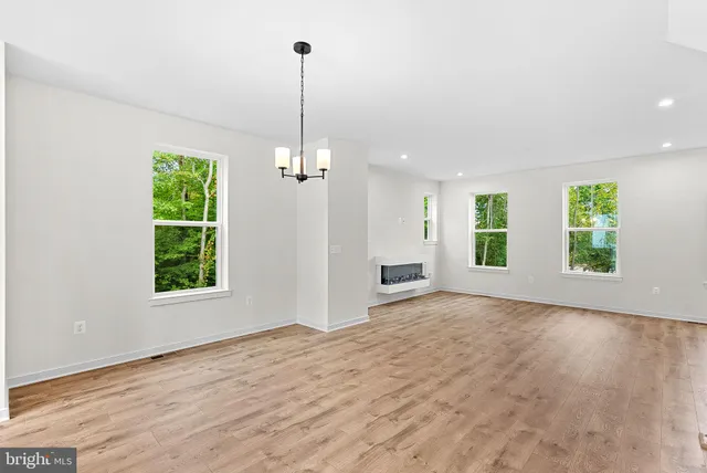 a view of an empty room with window wooden floor and chandelier