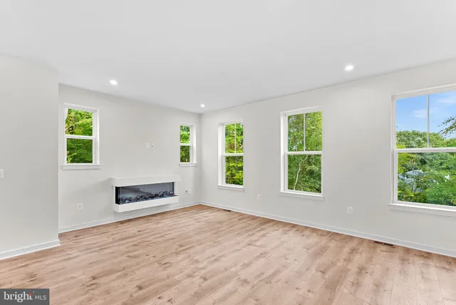 an empty room with windows and fireplace