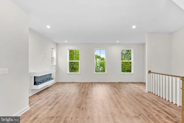 an empty room with windows & ceiling fan