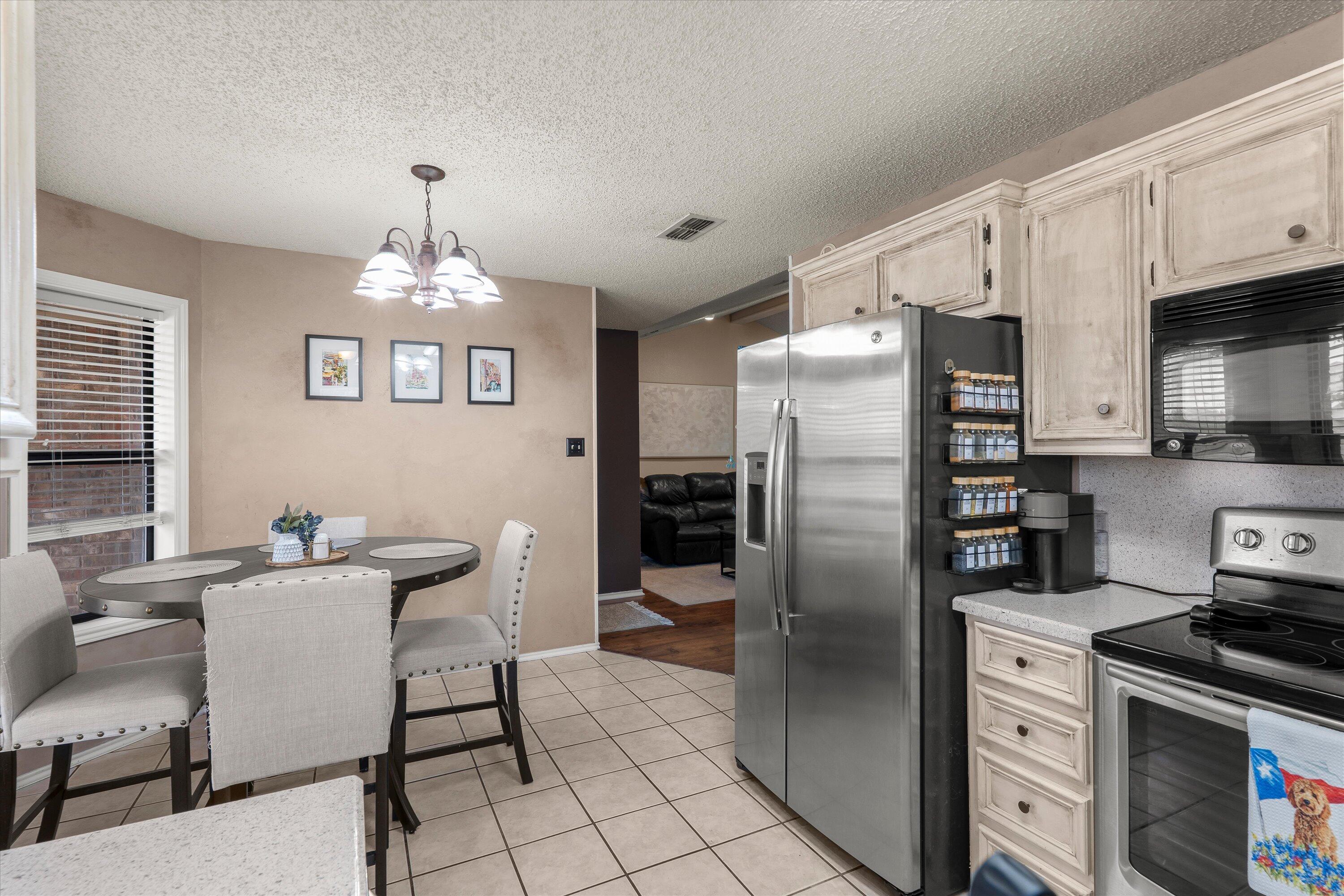 2308 93rd Street Lubbock, TX 79423 - Photo 13 of 28 a kitchen with stainless steel appliances a refrigerator a stove a sink cabinets and a dining table