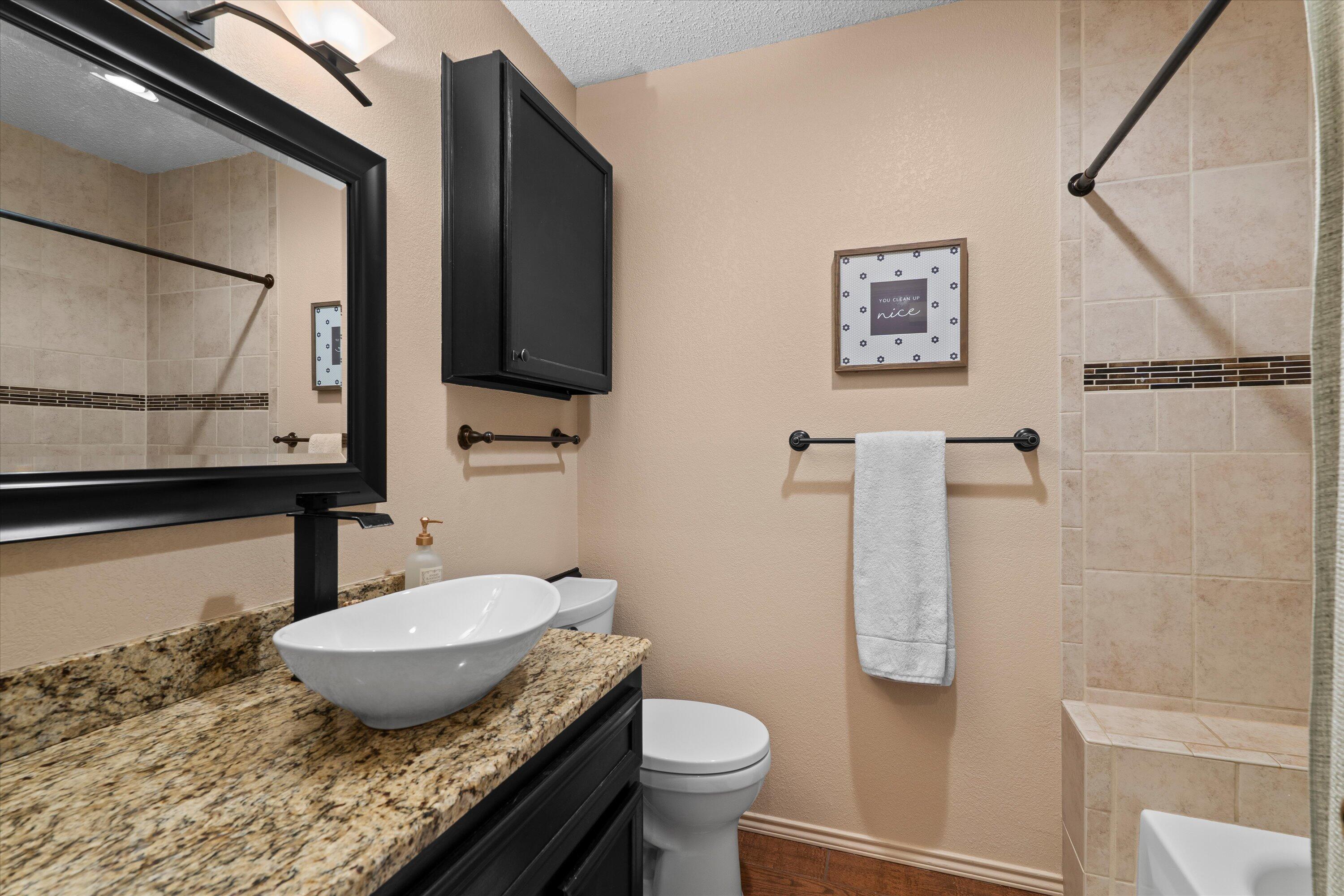 2308 93rd Street Lubbock, TX 79423 - Photo 20 of 28 a bathroom with a granite countertop sink toilet and mirror