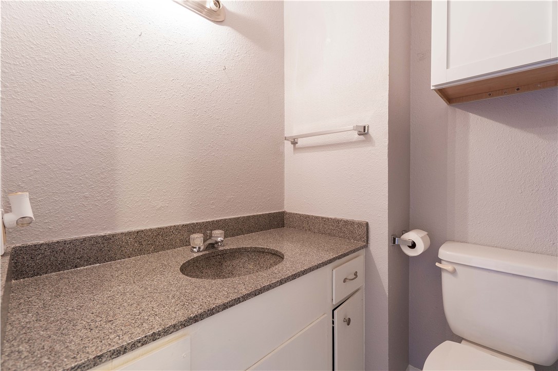 6232 Weber Road Corpus Christi, TX 78413 - Photo 19 of 23 a bathroom with a granite countertop sink a toilet and a mirror