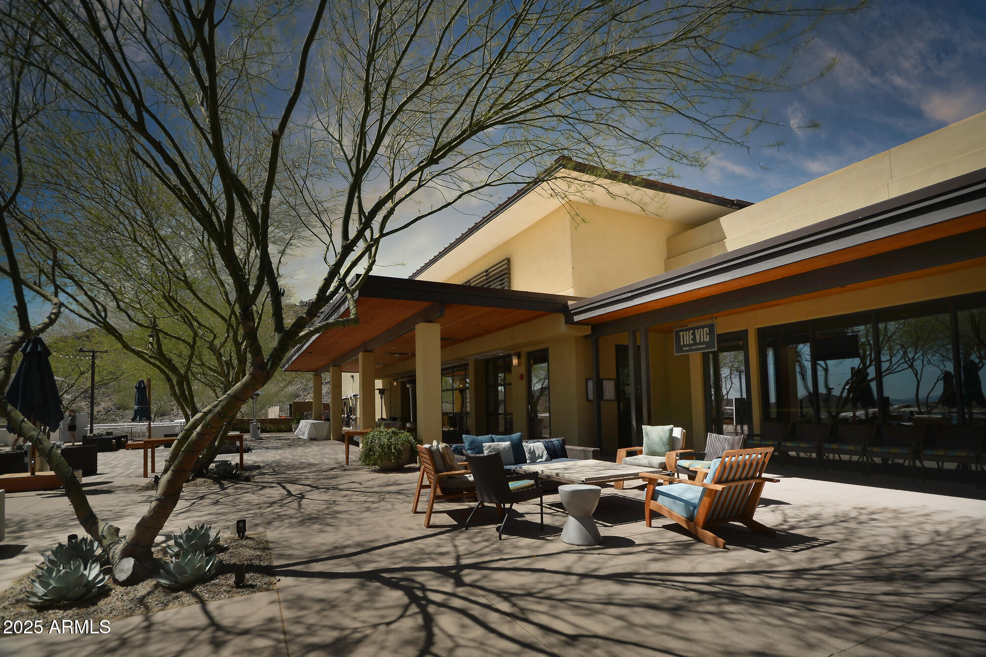 3294 North Springfield Street Buckeye, AZ 85396 - Photo 42 of 43 a view of a patio with couches and table and chairs under an umbrella with large trees