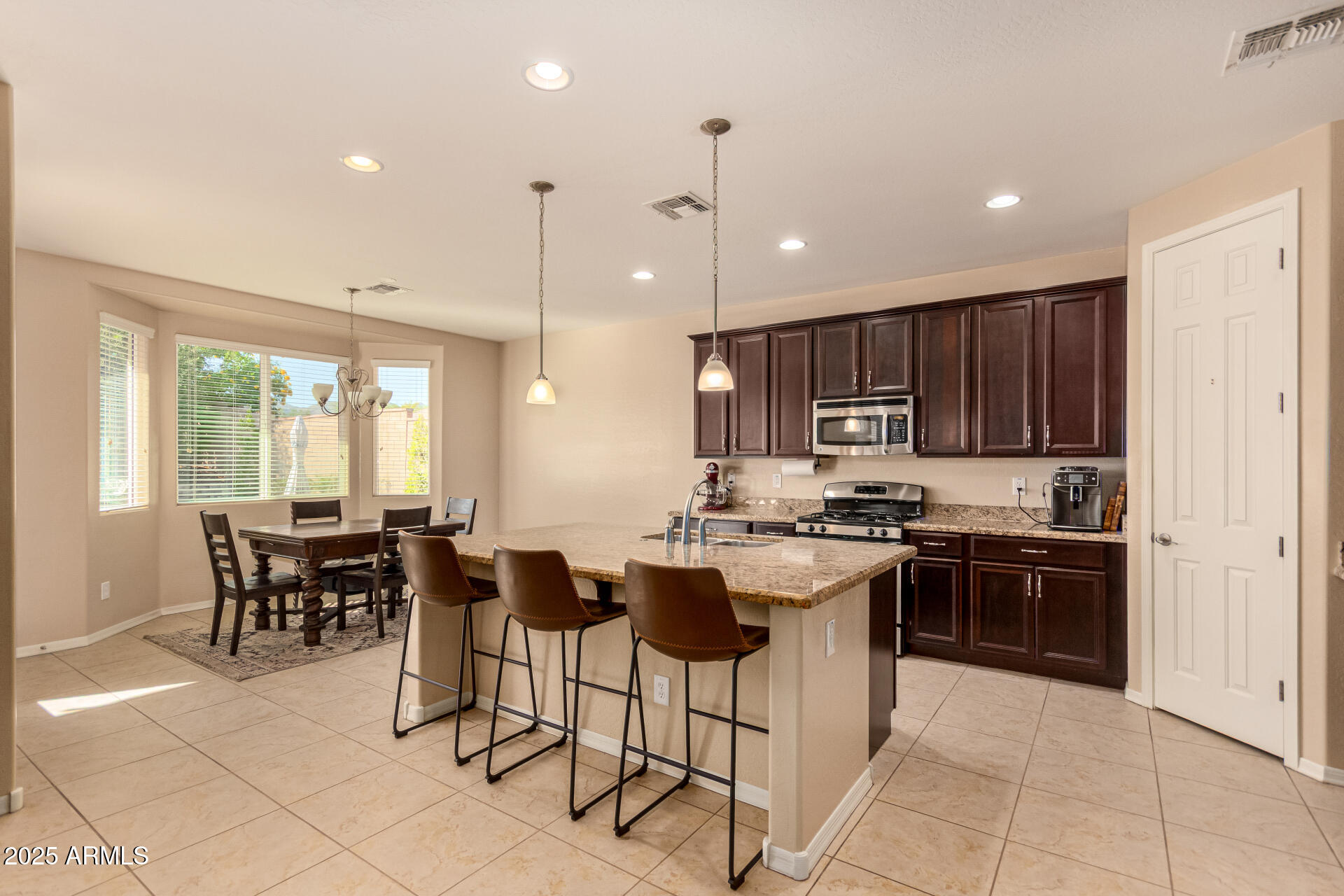3294 North Springfield Street Buckeye, AZ 85396 - Photo 10 of 43 a kitchen with kitchen island granite countertop wooden cabinets and stainless steel appliances