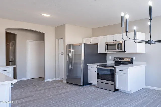 a kitchen with a sink dishwasher a stove and white cabinets with wooden floor
