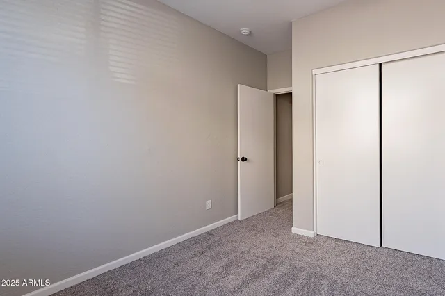 a view of an empty room with wooden floor and a ceiling fan