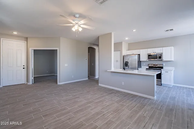 a view of an empty room with a window and a kitchen