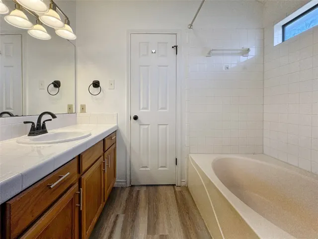 a bathroom with a tub sink and mirror