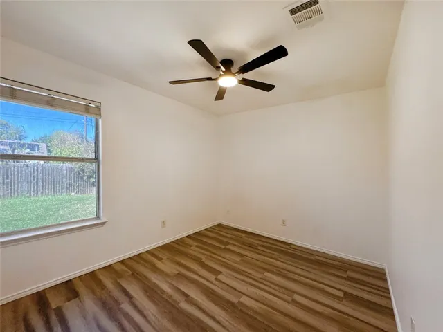 a view of a livingroom with a fireplace a ceiling fan and wooden floor