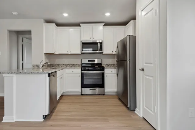 a kitchen with white cabinets and stainless steel appliances