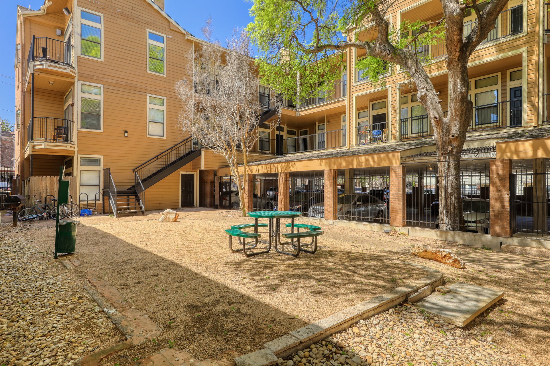 2802 Nueces Street, Unit 306 Austin, TX 78705 - Photo 2 of 20 Outdoor courtyard area featuring a picnic table, a mature tree providing natural shade, and gravel landscaping