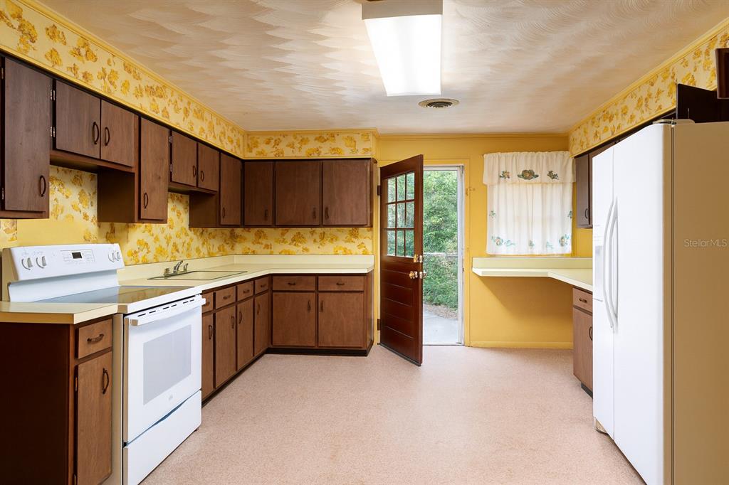 530 Southwest 23rd Avenue Ocala, FL 34471 - Photo 11 of 26 a kitchen with stainless steel appliances granite countertop a refrigerator a sink dishwasher and wooden cabinets with a large window