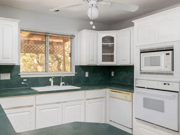 a kitchen with granite countertop white cabinets and white appliances