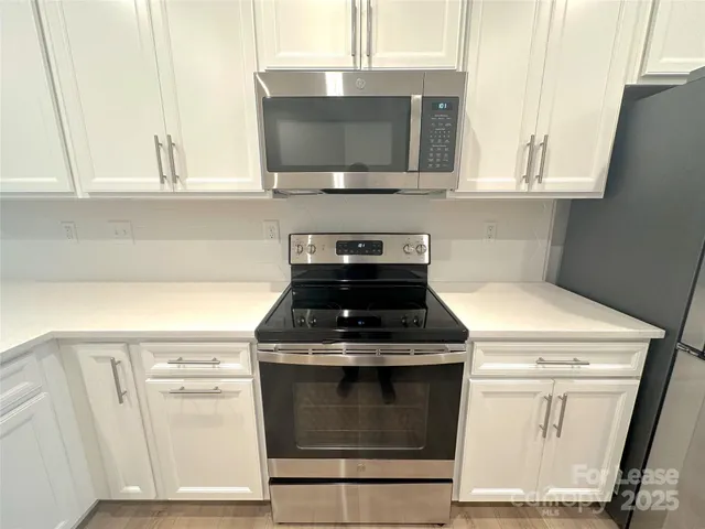 a kitchen with granite countertop white cabinets stainless steel appliances and sink