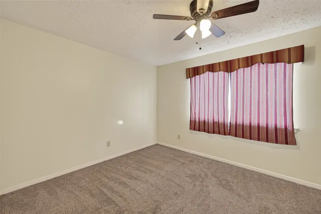 an empty room with chandelier fan and windows