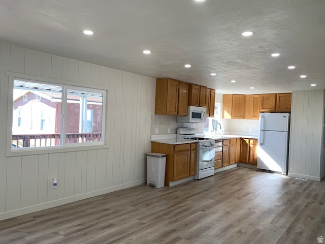 1500 North Angel Street West, Unit 56 Layton, UT 84041 - Photo 8 of 20 Kitchen with light countertops, wooden walls, white appliances, wood finish cabinets, and light wood-style floors