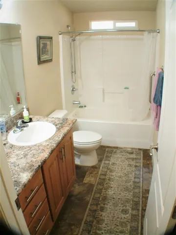 a bathroom with a granite countertop sink a toilet a mirror a bathtub and shower