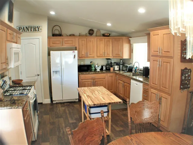 a kitchen with a refrigerator a stove a sink and a dining table with wooden floor